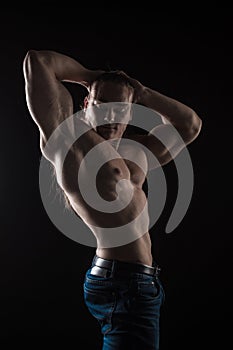 Naked torso male bodybuilder athlete with long blond hair in studio
