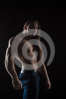 Naked torso male bodybuilder athlete with long blond hair in studio