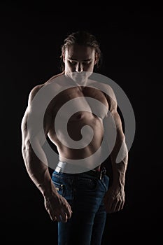 Naked torso male bodybuilder athlete with long blond hair in studio