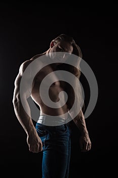 Naked torso male bodybuilder athlete with long blond hair in studio