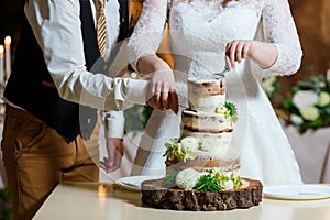 Naked wedding cake, decorated with fresh flowers, greenery. Delicious dessert at wedding banquet