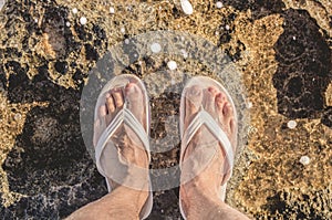 Naked wet male feet on the rocks washed by the sea wave