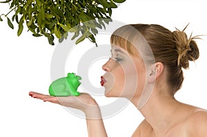 Naked woman kissing a frog under mistletoe