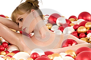 Naked woman lying in bath with Christmas balls photo