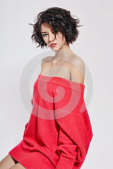 Naked woman with short hair. Girl posing in a red sweater on a white background. Perfect clean skin, Nude body of