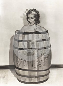 Naked woman sitting in wooden barrel