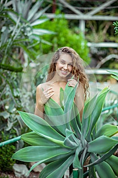 Naked woman standing near the plant and smiling