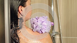 naked woman washing her shoulders in shower.