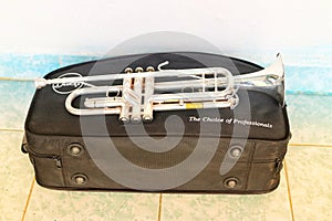 Nakhon Sawan, Thailand, on May 8, 2019, a silver trumpet blowing instrument placed on a black box.  On the tile floor