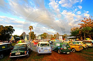 December 16, 2017: Many old Classic Mini Austin cooper parked on grass field with green tree and blue sky background