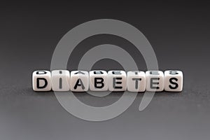 The name diabetes created by white beads on a gray background