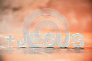 Name JESUS made with cement letters on orange light marble background. Copy space. Biblical, spiritual or christian