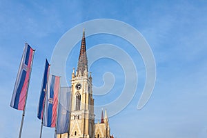 The Name of Mary Church, also known as Novi Sad catholic cathedral on a sunny afternoon with the flags of Voivodina province