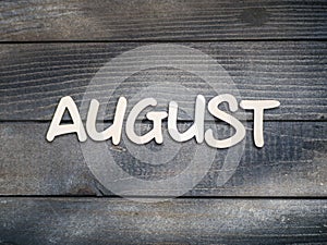 The name of the month is composed of light wooden letters on dark wood. The month of August.