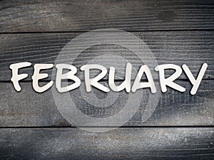 The name of the month is composed of light wooden letters on dark wood. The month of February.