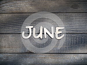 The name of the month is composed of light wooden letters on dark wood. The month of June.