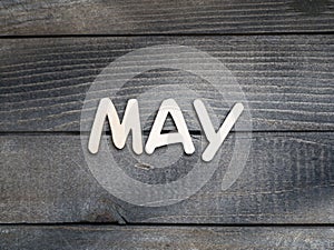 The name of the month is composed of light wooden letters on dark wood. The month of May.