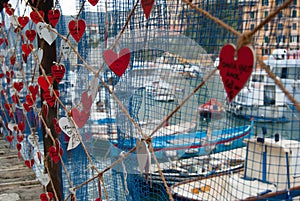 Names of lovers written on hearts hanging in a street of Camogli