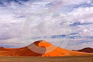 Namibia landscape. Big orange dune with blue sky and clouds, Sossusvlei, Namib desert, Namibia, Southern Africa. Red sand, biggest