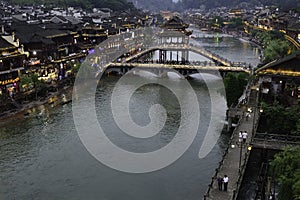 The Nanhua Bridge lights up as dusk falls on the water town Fenghuang Ancient City in Tibet