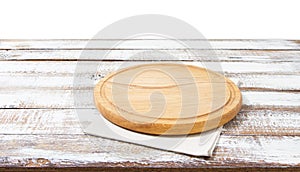 Napkin and board for pizza on wooden desk. Stack of colorful dish towels on white wooden table background top view mock up.