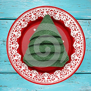 Napkin folded in the shape of a Christmas tree in a red plate