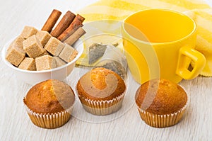 Napkin, muffins, teacup, bowl with cinnamon and sugar, tea bags