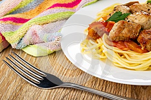 Napkin, plate with pieces of fried pork meat with lecho and spaghetti, fork on table