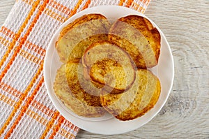 Napkin, plate with toasted slices of bread on wooden table. Top view