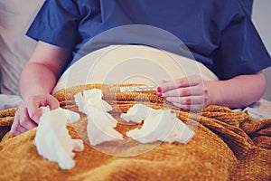 Napkins and handkerchiefs on the lap of a woman with coronavirus. Thermometer in the hands of a girl with a runny nose