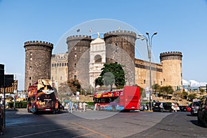 Castel Nuovo with tourist buses parked in front and clear blue sky