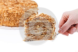 Napoleon cake, with a cut out slice on the spatula in hand, on white background isolated