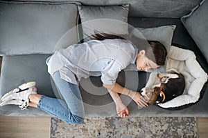 A young woman lying next to her puppy and having a nap