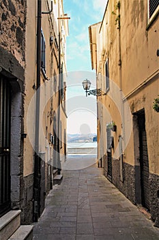 Narrow alley of Marta fishermen burg with landscape of Bolsena lake