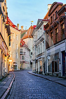 Narrow alley of medieval houses in the city of Tallinn at sunrise.