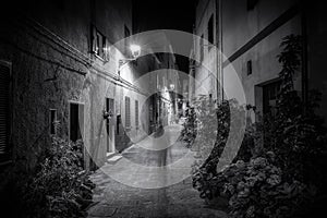 Narrow alley in the old town of Catselsardo on Sardinia at night in black and white