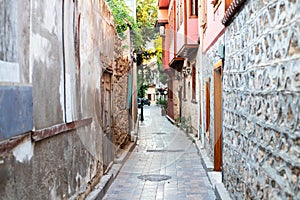 Narrow alley in the old town. Curved walls of houses in a narrow street. Old walls and doors in a narrow passage of a European