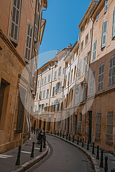 Narrow alley with tall buildings in the shadow in Aix-en-Provence.