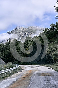 narrow bad road through the forest next to the trees in the direction of the impressive rocky mountains, ruta del cares