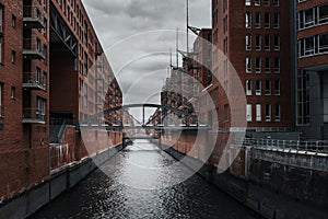 a narrow canal running through a city near tall buildings and a bridge, Hamburg, Germany