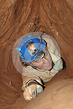 Narrow cave passage with caver photo