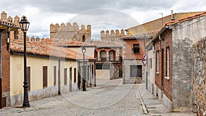 Narrow cobbled street in Avila, Spain, with old medieval buildings.