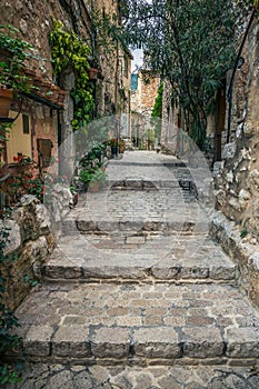 Narrow cobbled street with flowers in the old village , France.