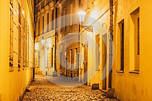 Narrow cobbled street illuminated by street lamps of Old Town, Prague, Czech Republic