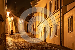 Narrow cobbled street in old medieval town with illuminated houses by vintage street lamps, Novy svet, Prague, Czech