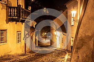 Narrow cobbled street in old medieval town with illuminated houses by vintage street lamps, Novy svet, Prague, Czech