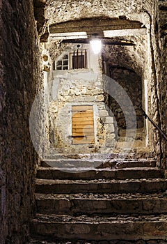 Narrow cobbled street in old town Peille at night.