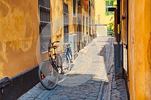 The narrow cobblestone street with a bicycle and yellow medieval houses of Gamla Stan historic old center of Stockholm at summer