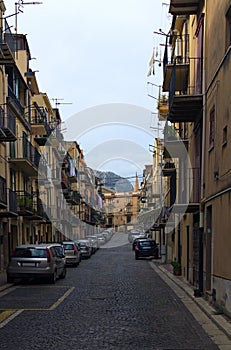 Narrow cobblestone street with densely parked cars. Typical Sicilian street with old residential houses