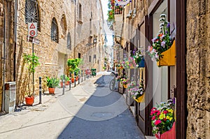 Narrow cobblestone street in Taranto historical city center. Typical italian street with flowers in pots photo